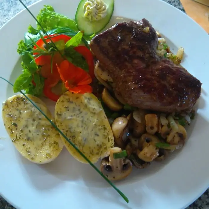 creation thumb for Rumpsteak  auf Im Rotwein geschmorten Champions-Zwiebeln Gemüse an einem  Salatbouquet mit Kräuterbutter Brötchen.
