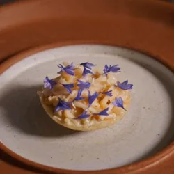 A crab chalupa topped with blue flowers