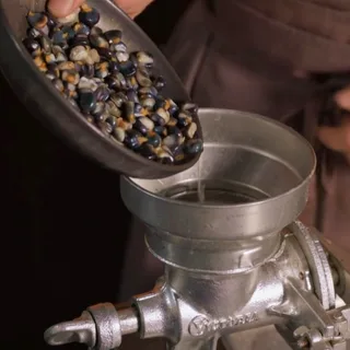 Pouring dried blue corn into a hand grinder