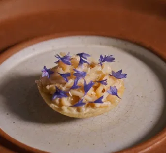 A crab chalupa topped with blue flowers