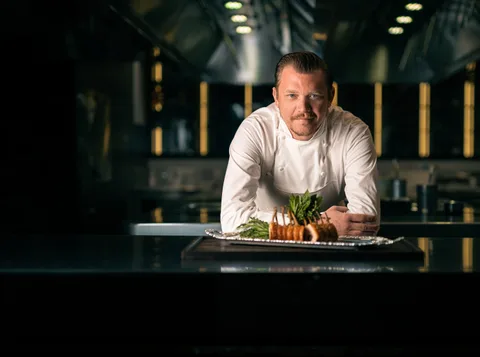 Chef Alex Dilling plating a lobster pithivier with sauce at the pass
